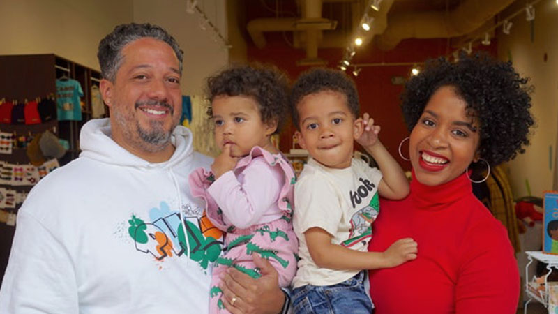 Father and mother holding their two kids while standing in a kids store.