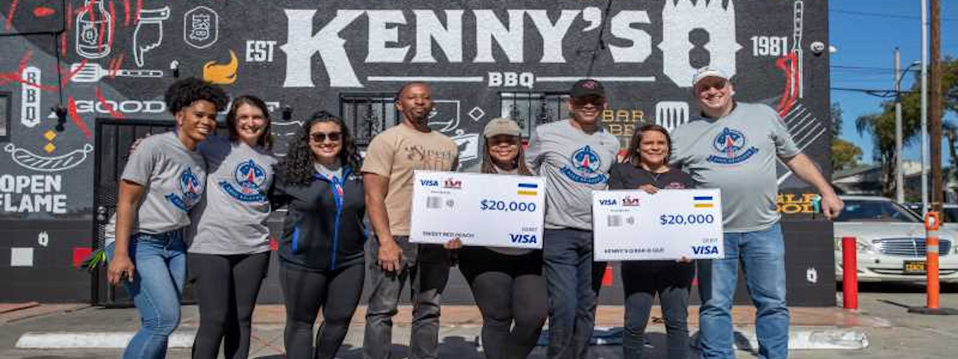 Kenny's BBQ employees holding grant checks outside of restaurant