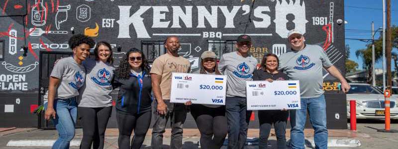 Kenny's BBQ employees holding grant checks outside of restaurant