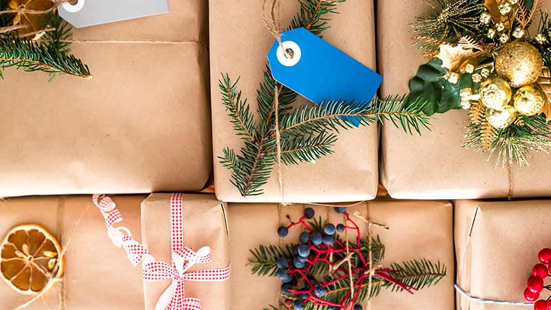 Christmas gifts packed in craft paper with a decoration made of fir branches, dried orange and berries.