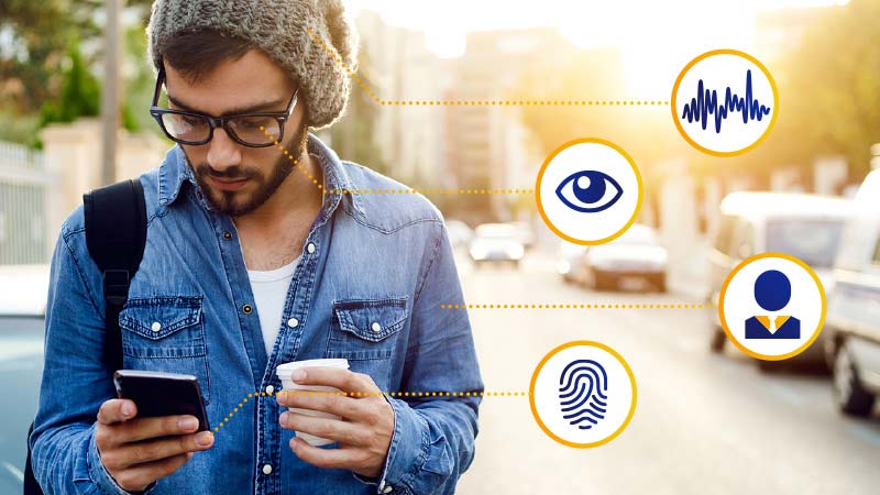 Man looking at his phone with biometric icons to the right. 