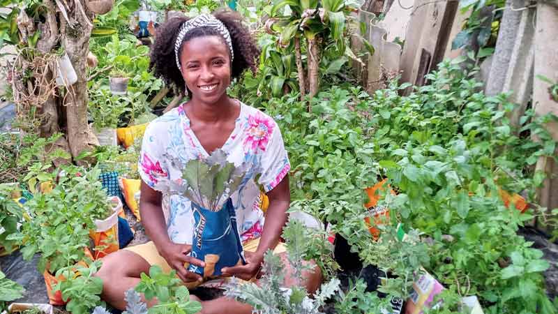 Leirilane Mendes stands among her plants in her medicinal garden