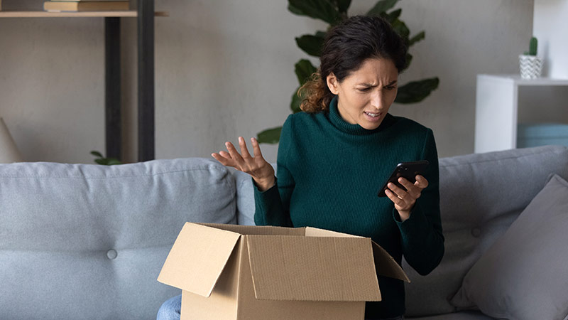 Woman opening a package looking confused at her phone