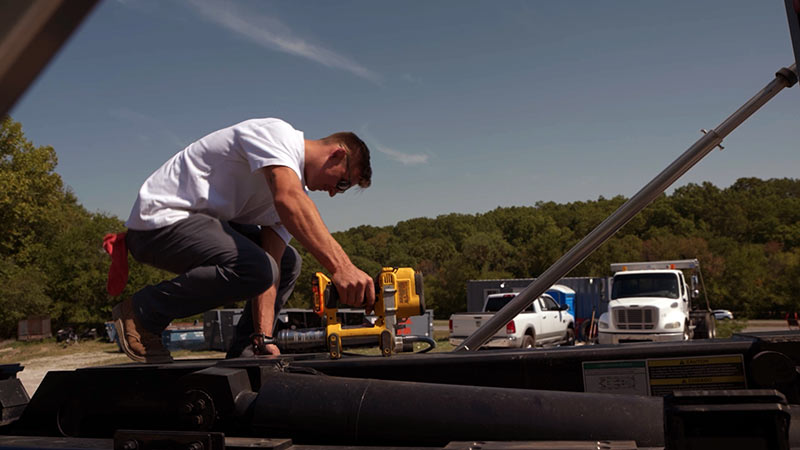 Small business owner in Oklahoma using a power tool on a truck