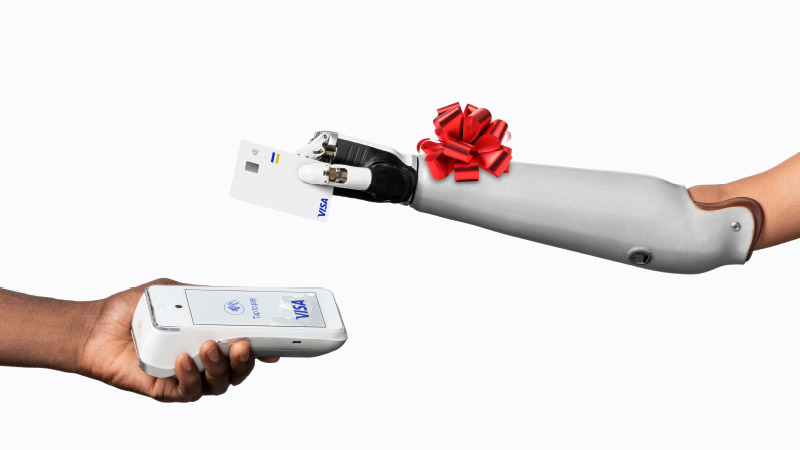 Person with prosthetic arm adorned with red bow taps to pay with Visa card