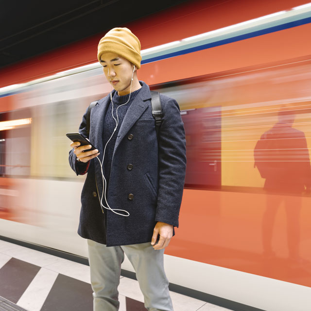 Man looking at phone in front of a train