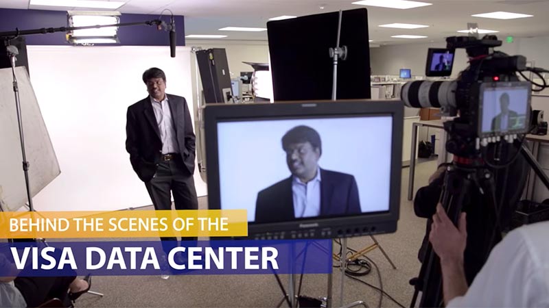Behind the scenes of Visa Data center with cameras in the background and a man facing the cameras.