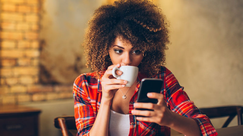 Woman drinking her coffee and checking her phone