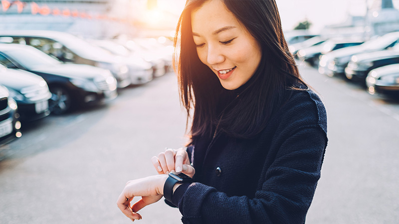 Woman standing in a parking lot looking at her watch. Woman standing in a parking lot looking at her watch.
