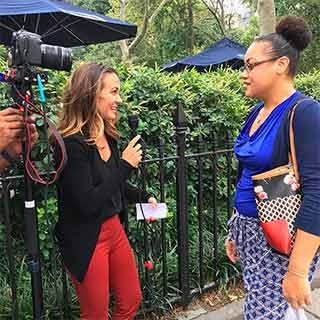 A female reporter interviewing another woman on the street.