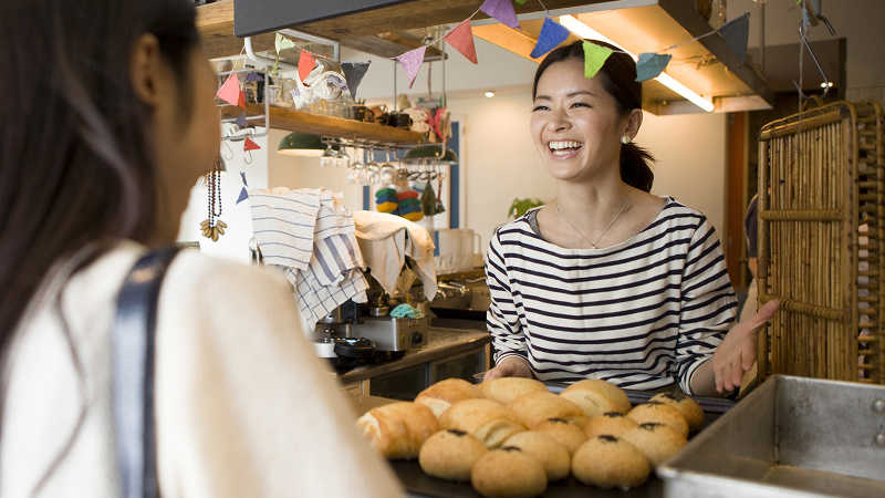 Women chatting and laughing at bakery counter.