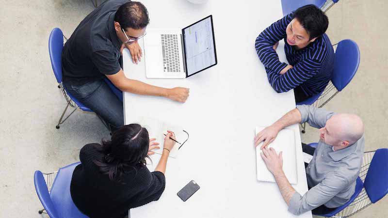 Overheat shot of Visa designers discussing a project at a table.