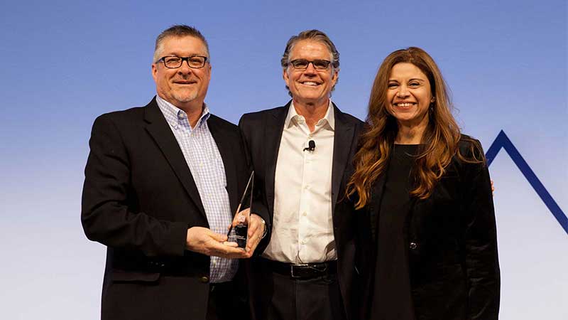 Man standing with male and female award winners.
