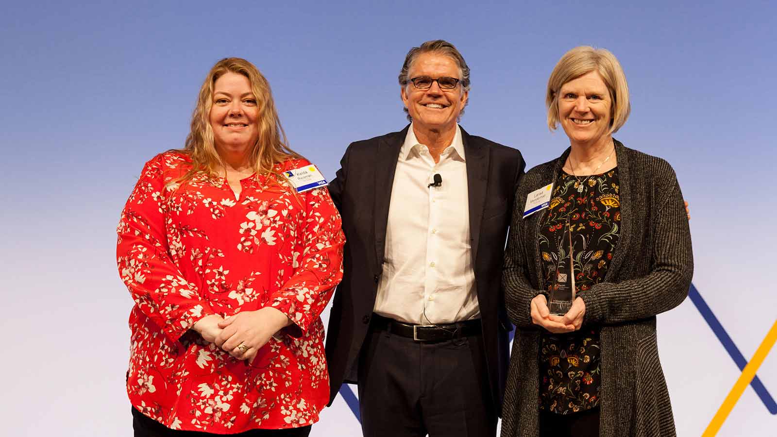 Man standing with two female award winners. 