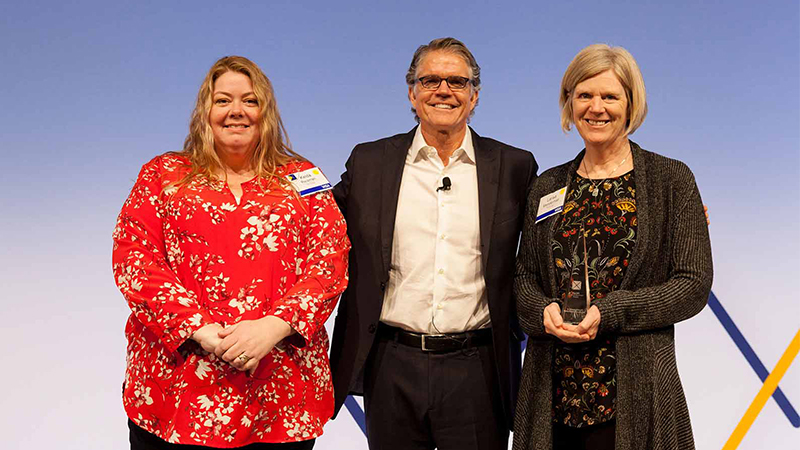 Man standing with two female award winners.