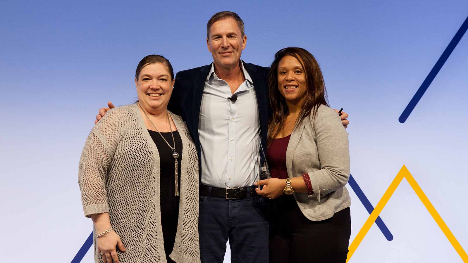 Man standing with two female award winners. 