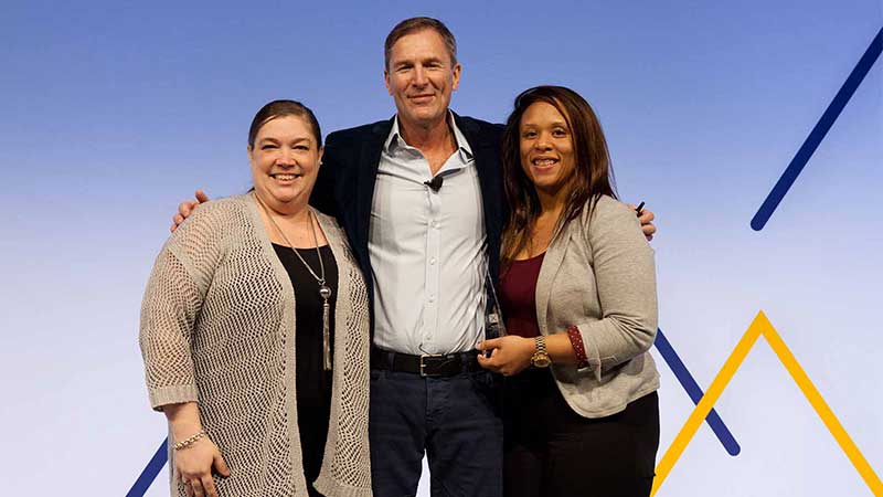 Man standing with two female award winners.