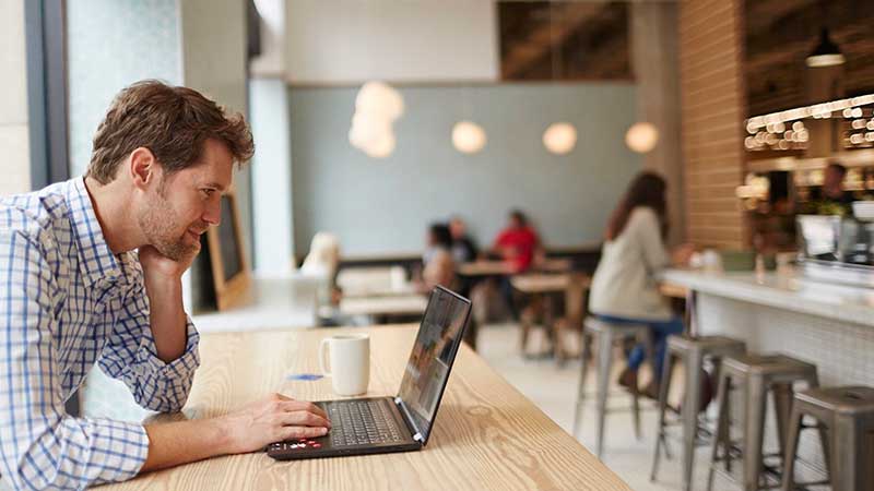 Man viewing his laptop at cafe while having coffee. Man viewing his laptop at cafe while having coffee.
