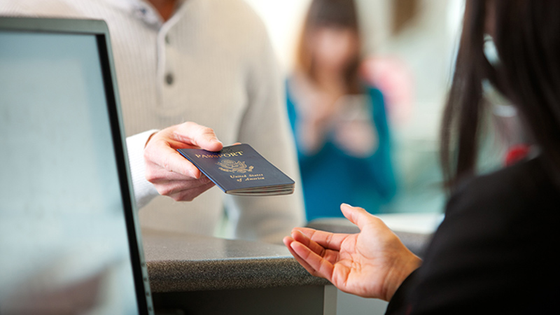 A traveler handing a United States passport over to an agent.