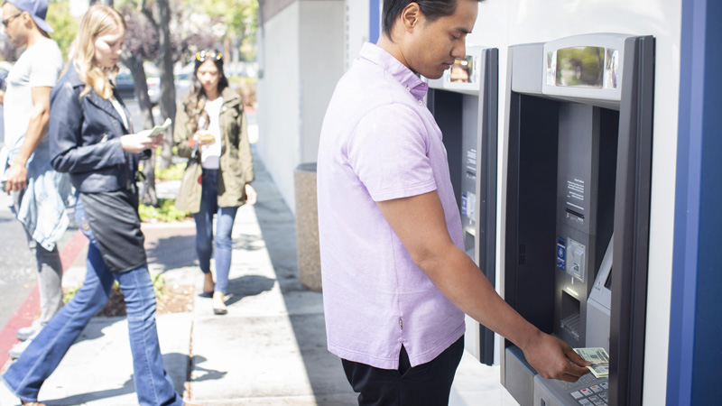 Man making a cash deposit at an ATM. Man making a cash deposit at an ATM.