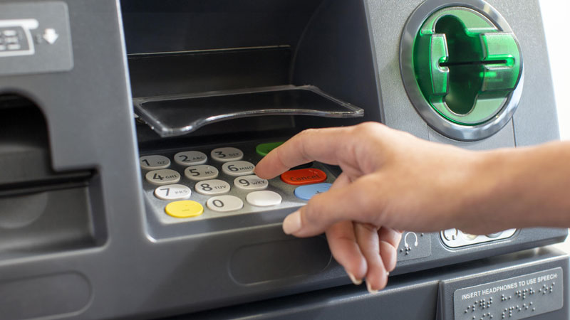 Closeup of a woman’s hand at an ATM.